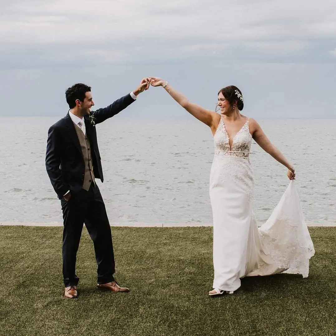 Bride and groom smiling at each other near a body of water